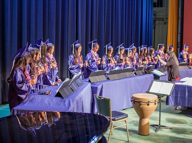 People in graduation gowns playing handbells