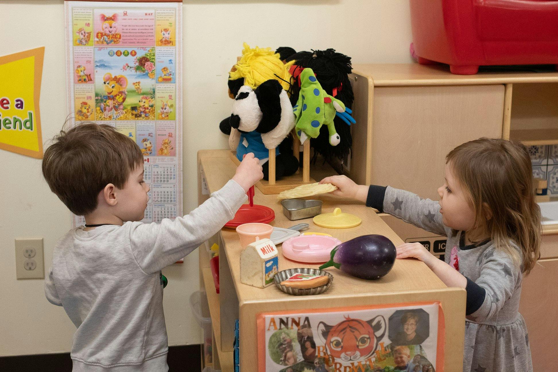 Two children playing with toy food at a small table