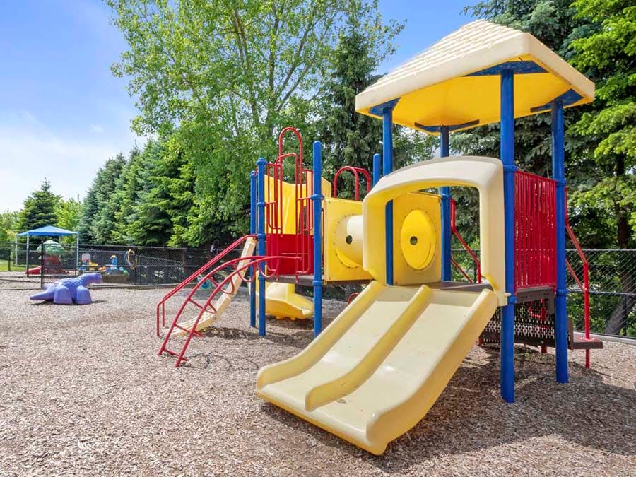 Colorful playground with yellow slides and blue poles on wood chips