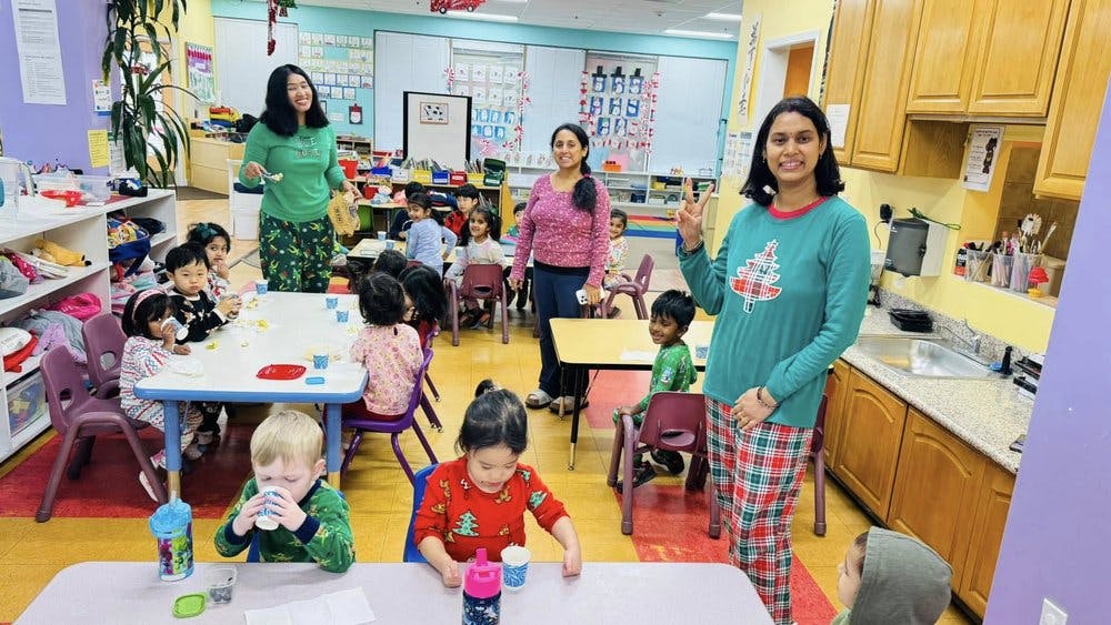 People and children in a classroom, some seated at tables
