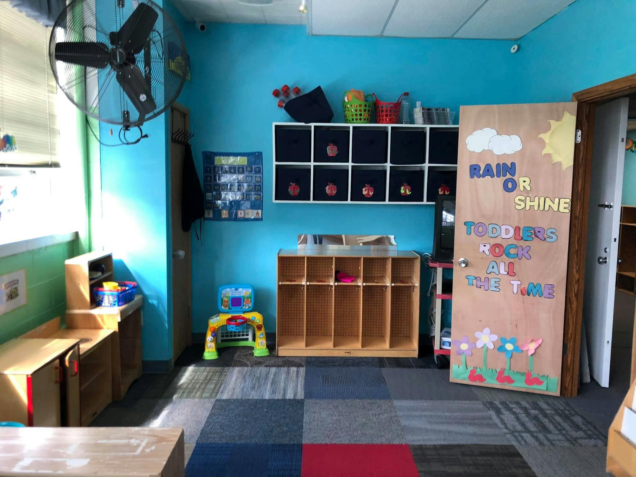 Classroom with cubbies, shelves, and a decorated door with text