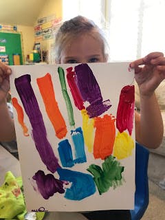 Child holding up a painting with colorful brushstrokes