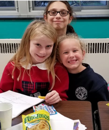 Three children smiling at a table