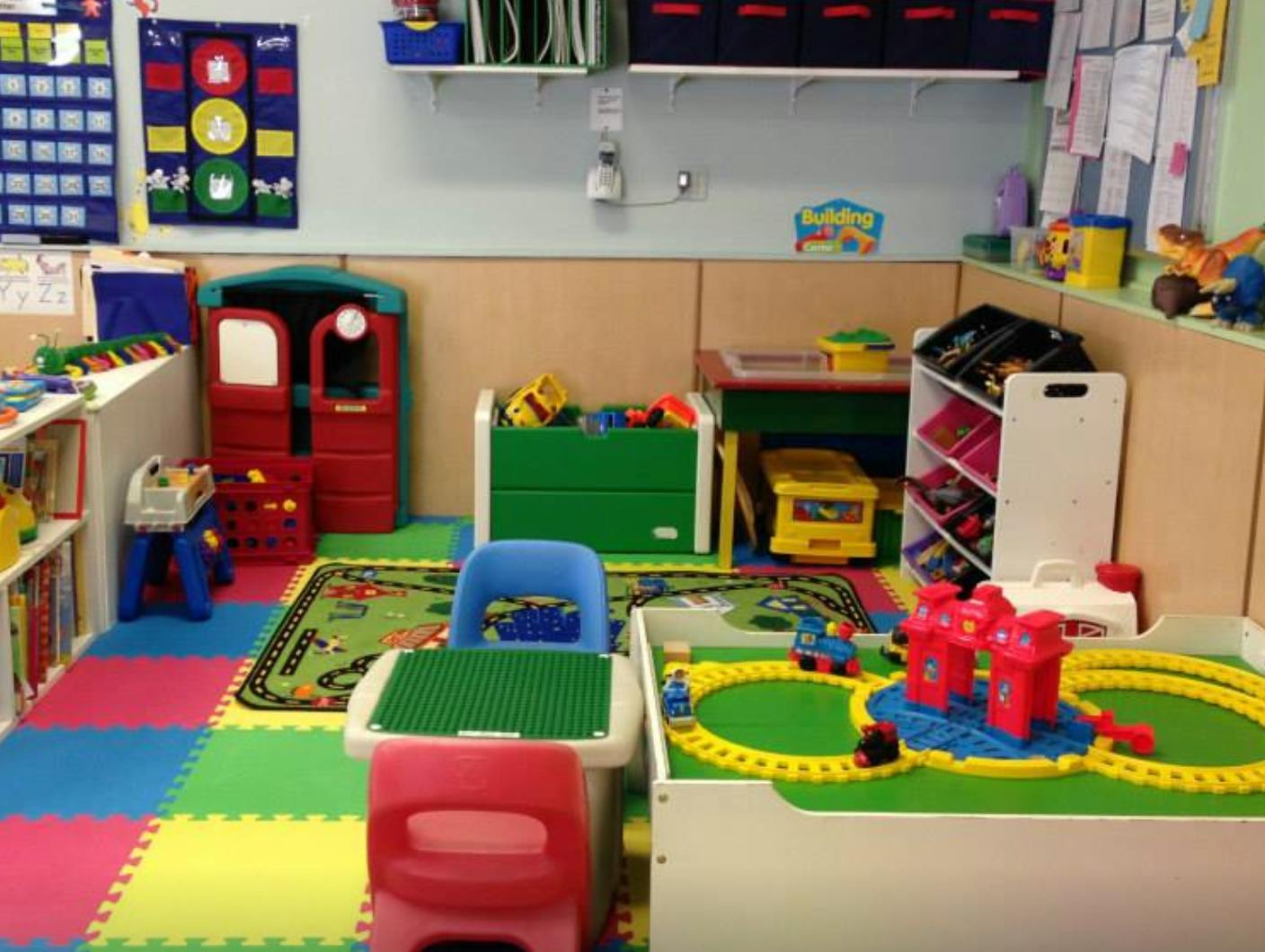 Playroom with colorful floor mats, toys, and child-sized furniture