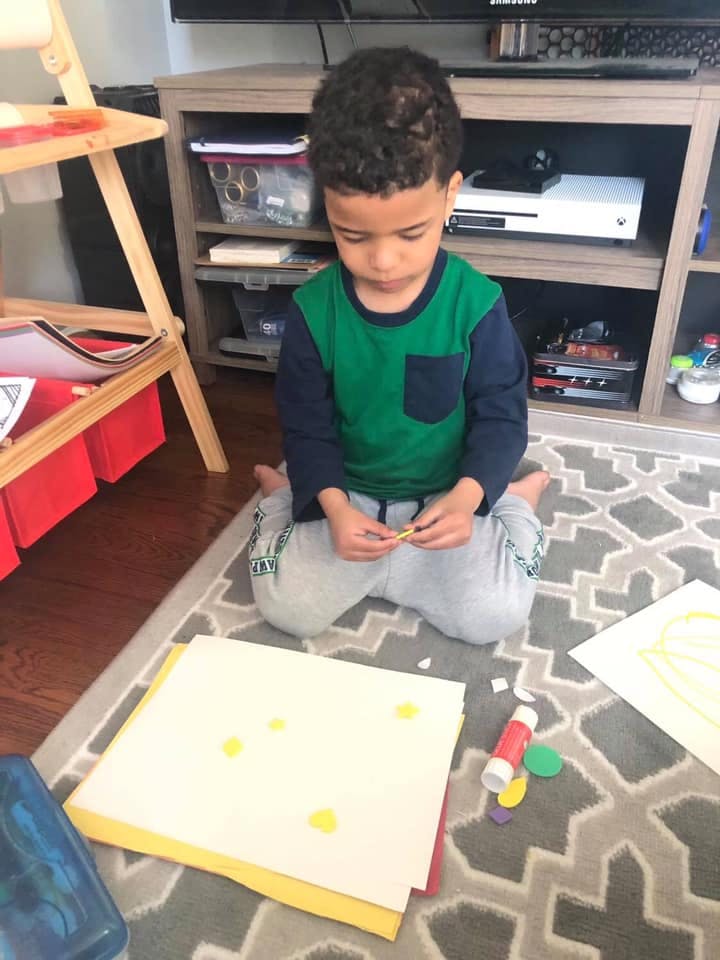 Child on floor doing crafts with paper and glue