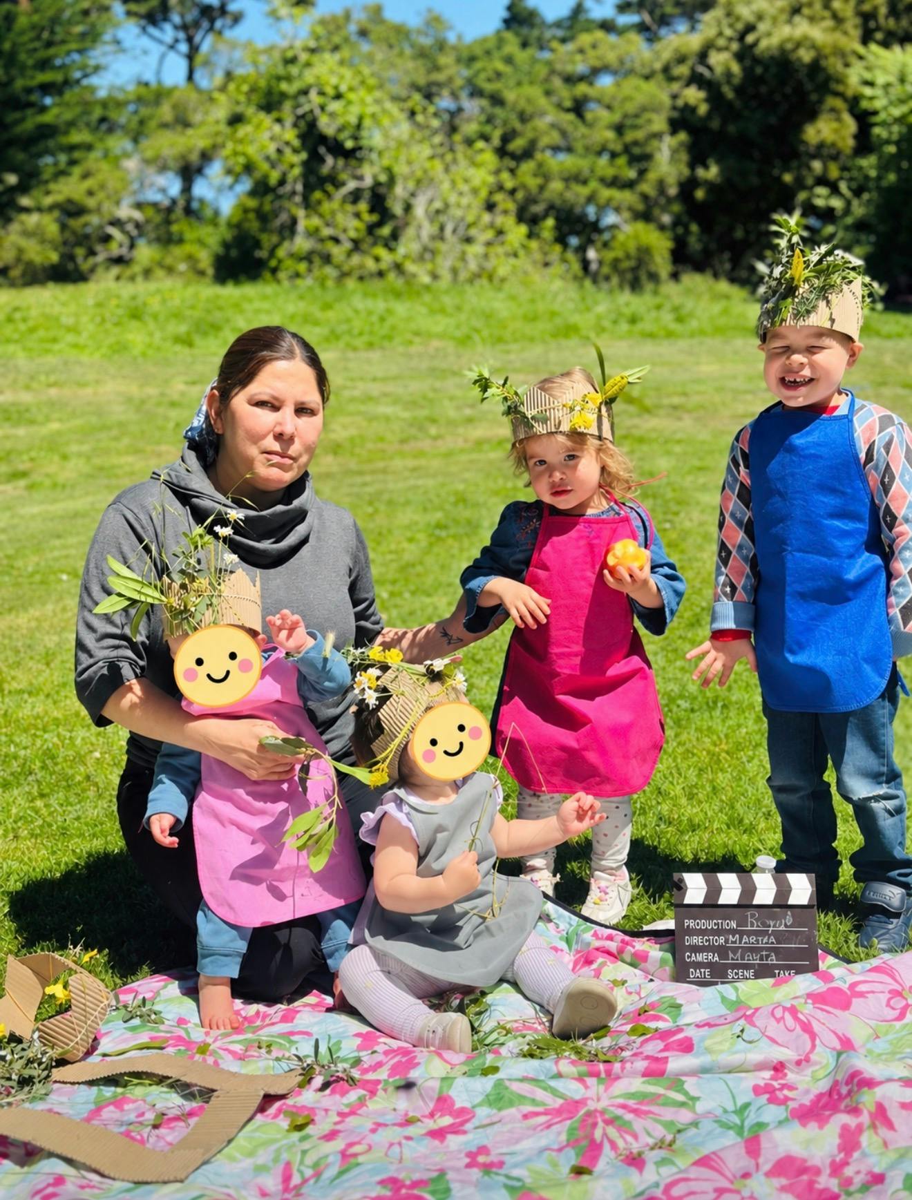 Adult and children wearing crowns on a blanket outdoors