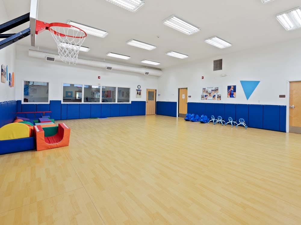 Indoor play area with a basketball hoop, soft play equipment, and ride-on toys