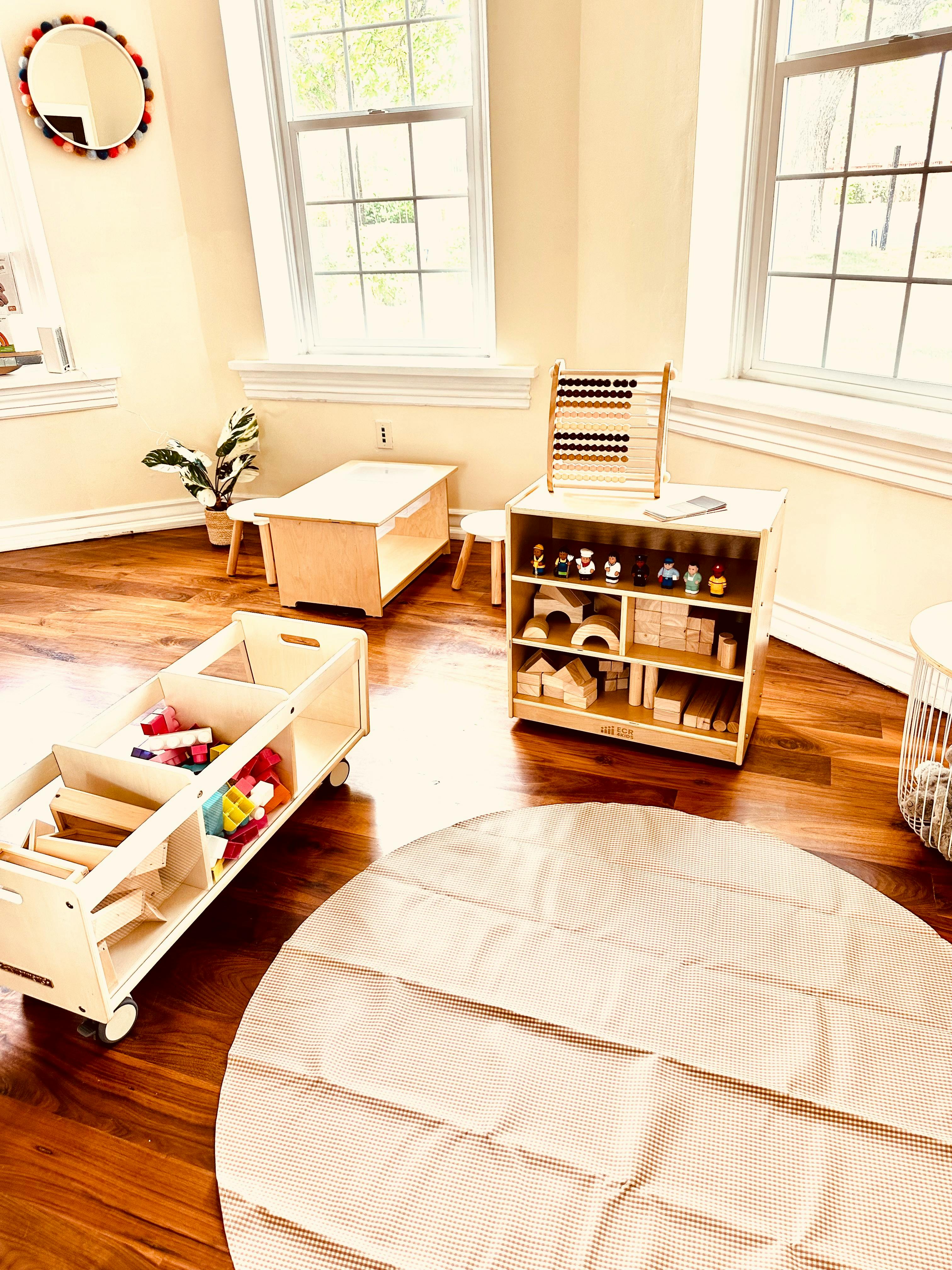 Playroom with wooden toys, furniture, and a round rug