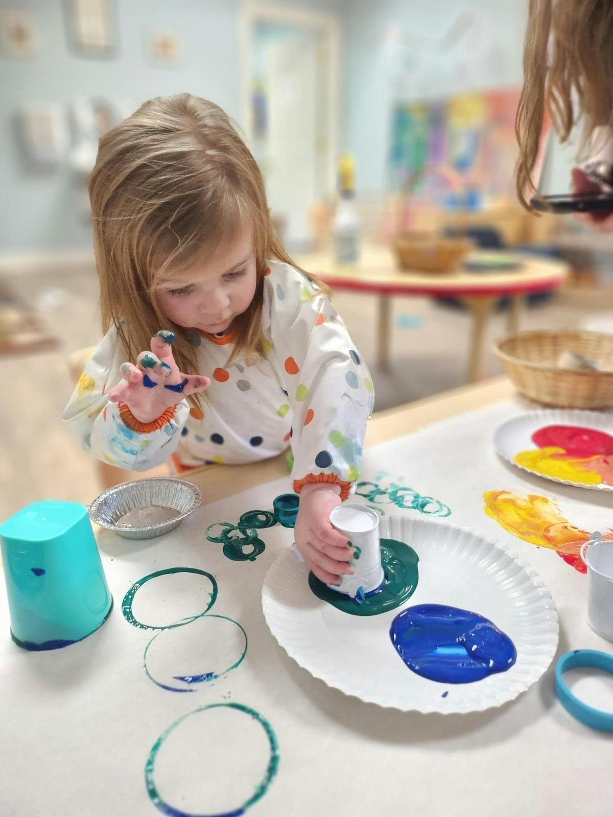 Child making art with paint and cups