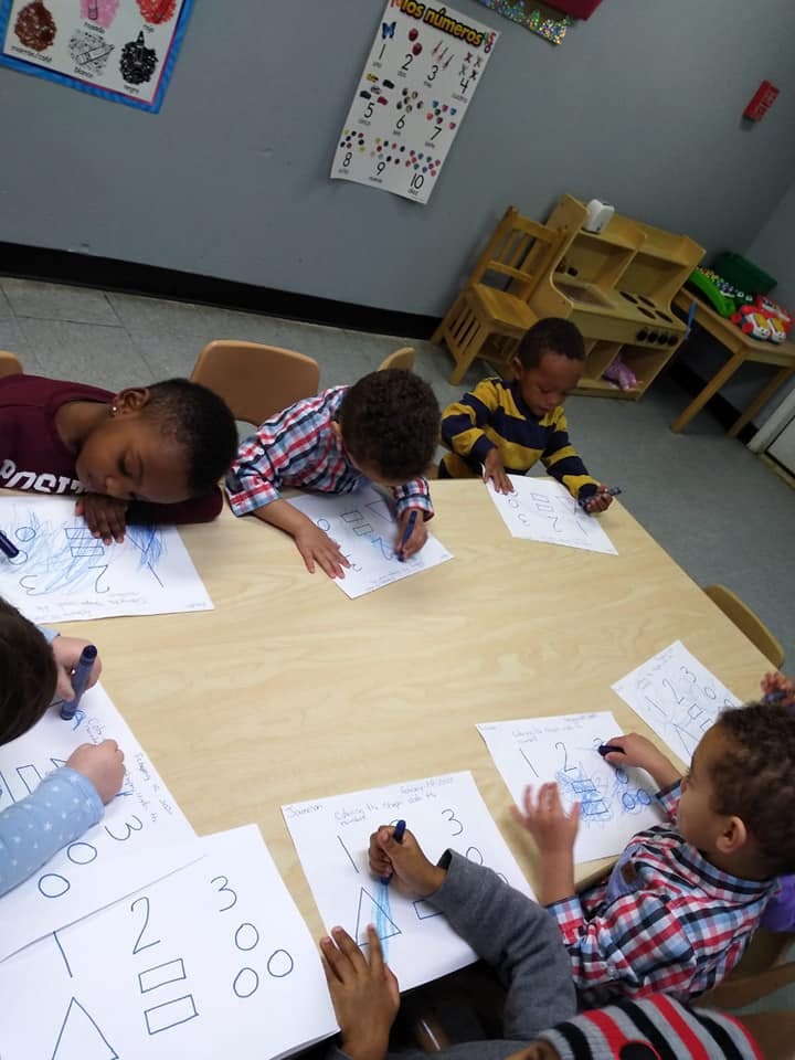 Children drawing and coloring at a table in a classroom