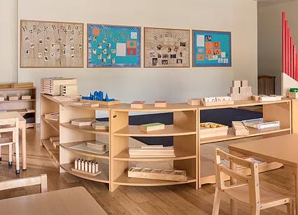 Classroom with wooden shelves holding learning materials and wall displays