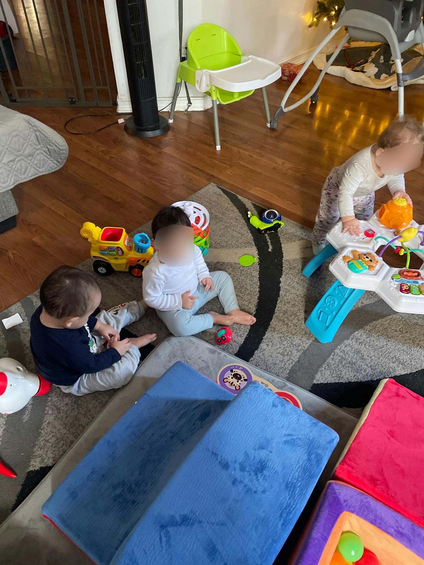 Three children playing with various toys on a living room rug
