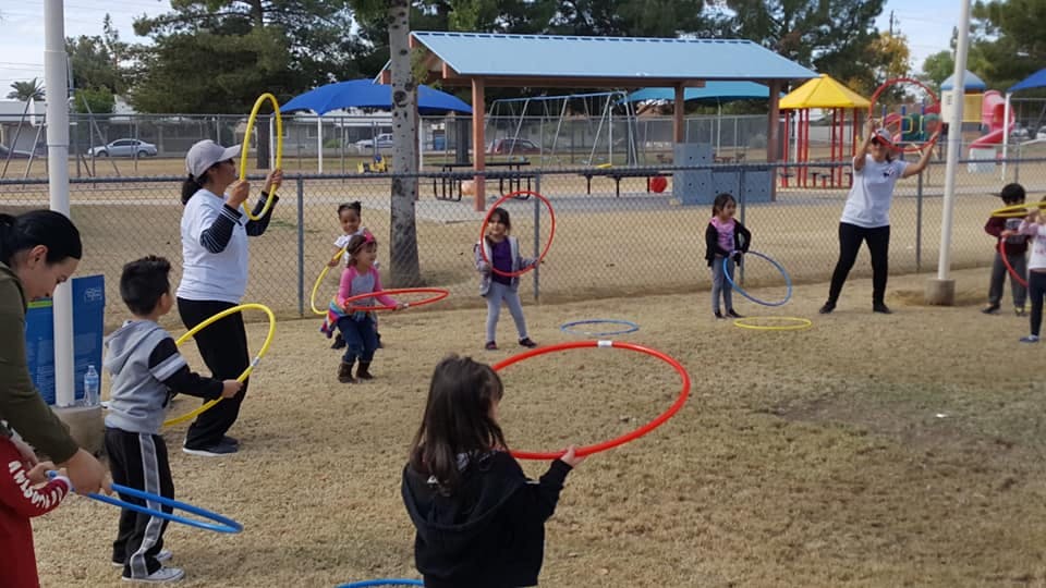 People and children playing with hula hoops outdoors