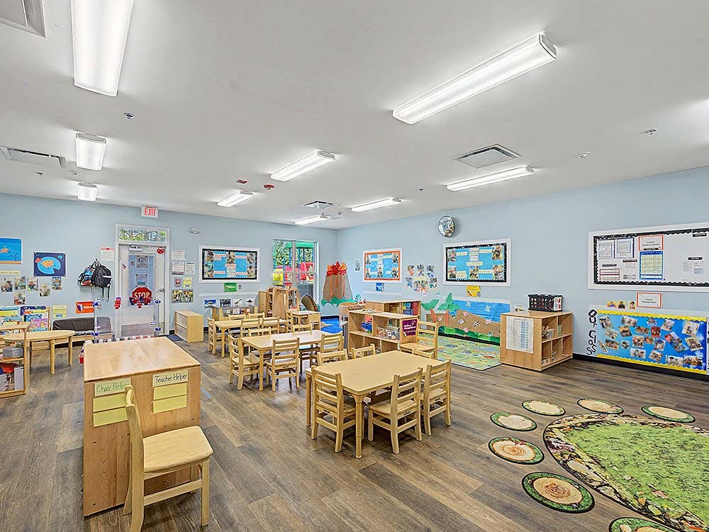 Empty children's classroom with small wooden tables and chairs