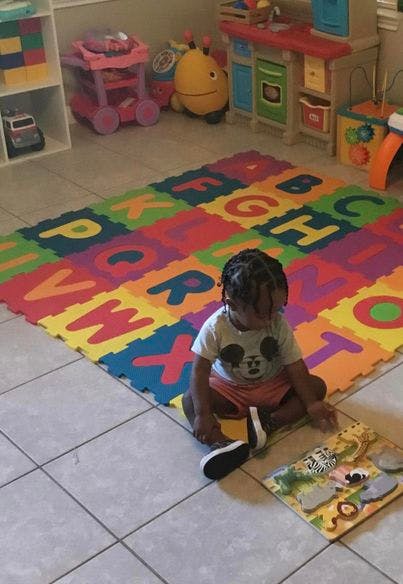 Child sitting on an alphabet mat playing with a puzzle