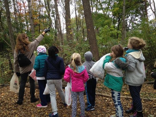 Adult and children in a wooded area, adult pointing up