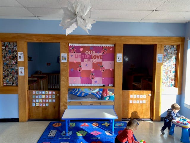 Children playing in a classroom with a bulletin board and small tables