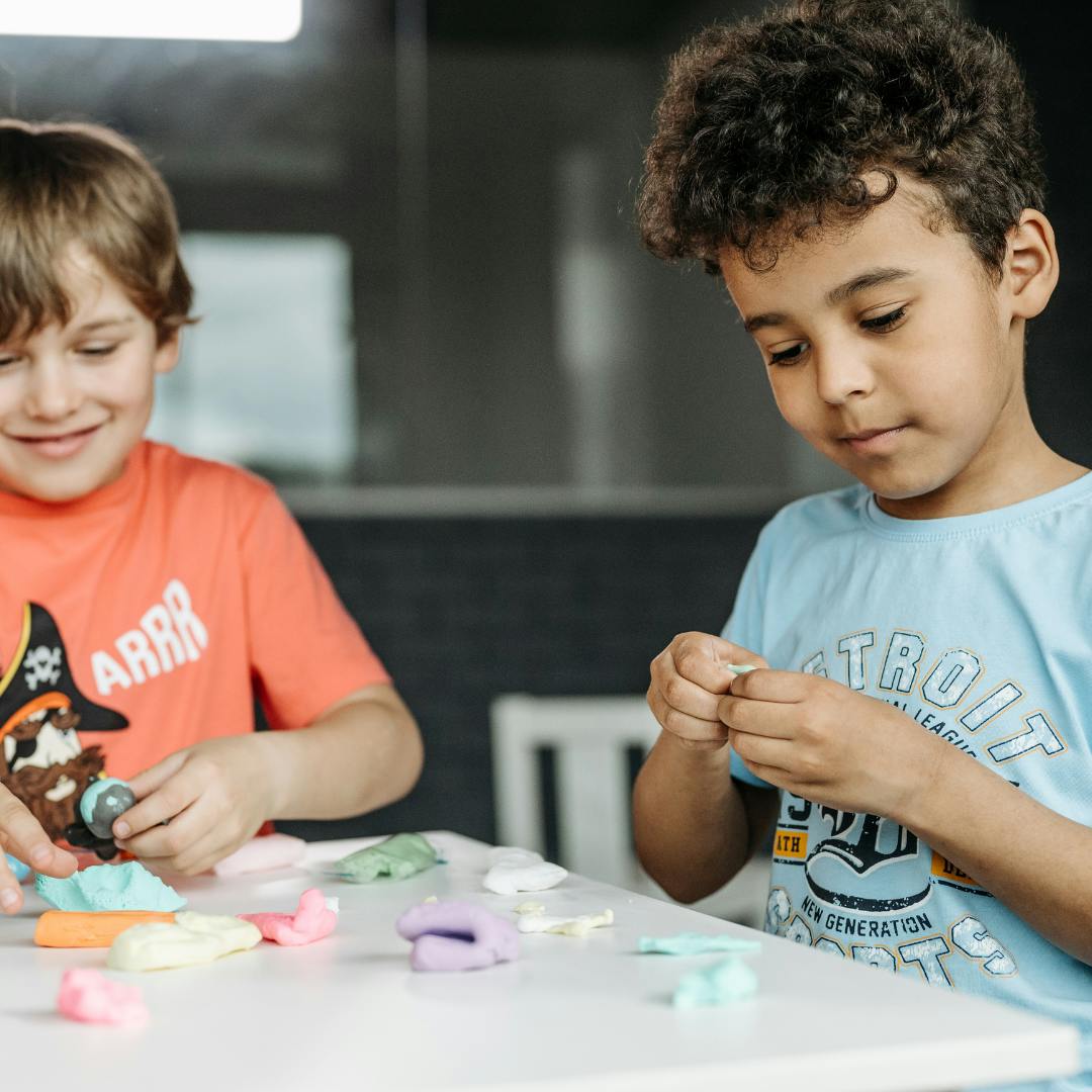 Two children playing with colorful modeling clay at a table