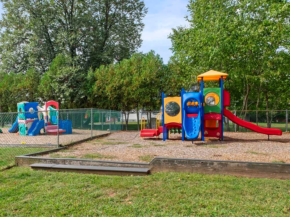 Fenced playground with colorful slides and climbing structures