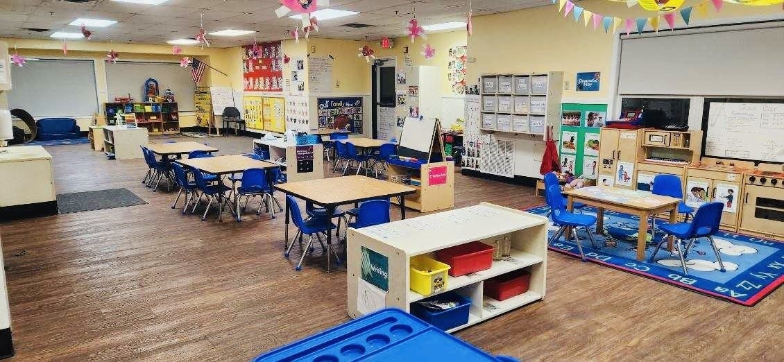 Empty classroom with small tables and chairs, and play areas