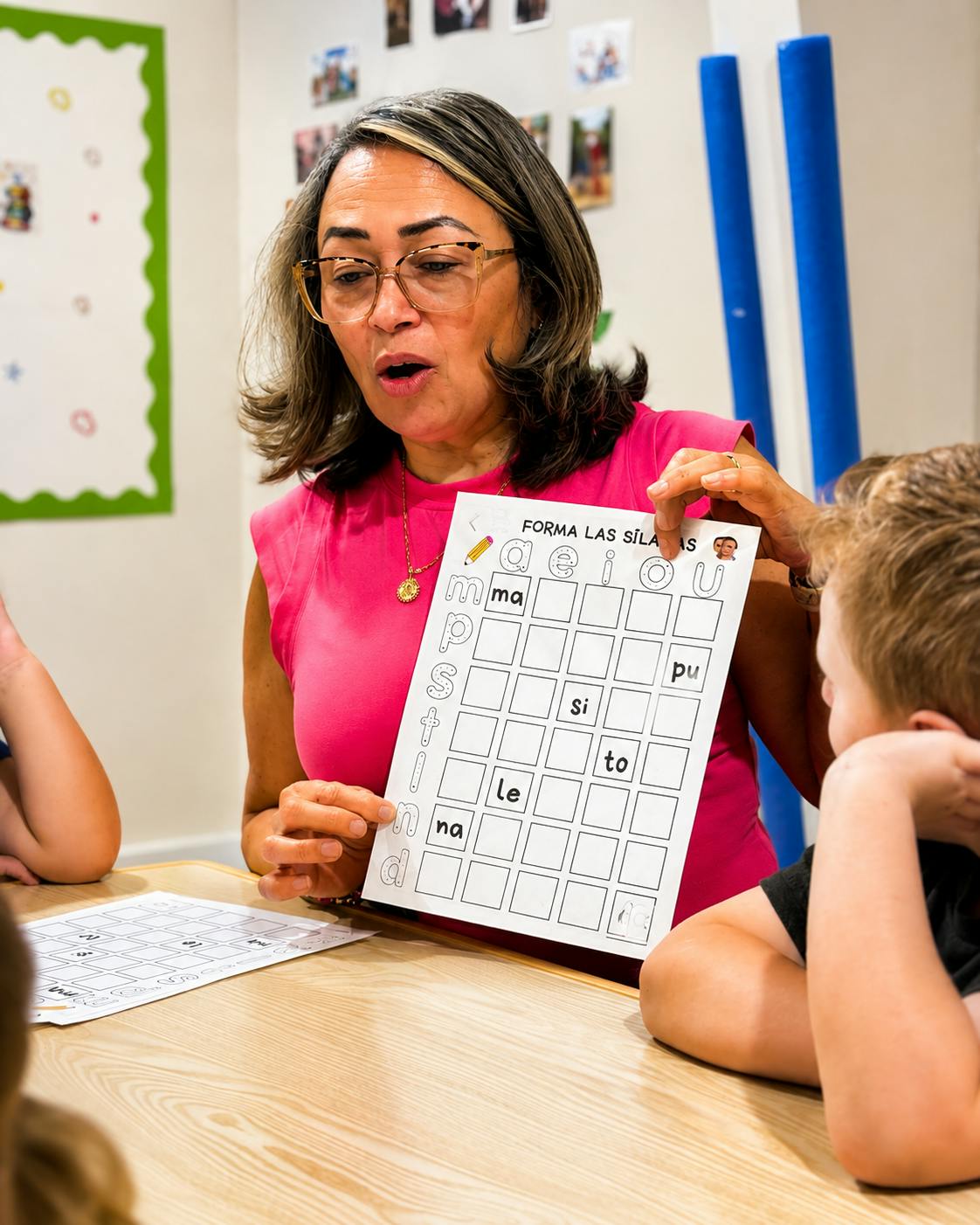 Teacher holding a Spanish syllable worksheet for a child in a classroom