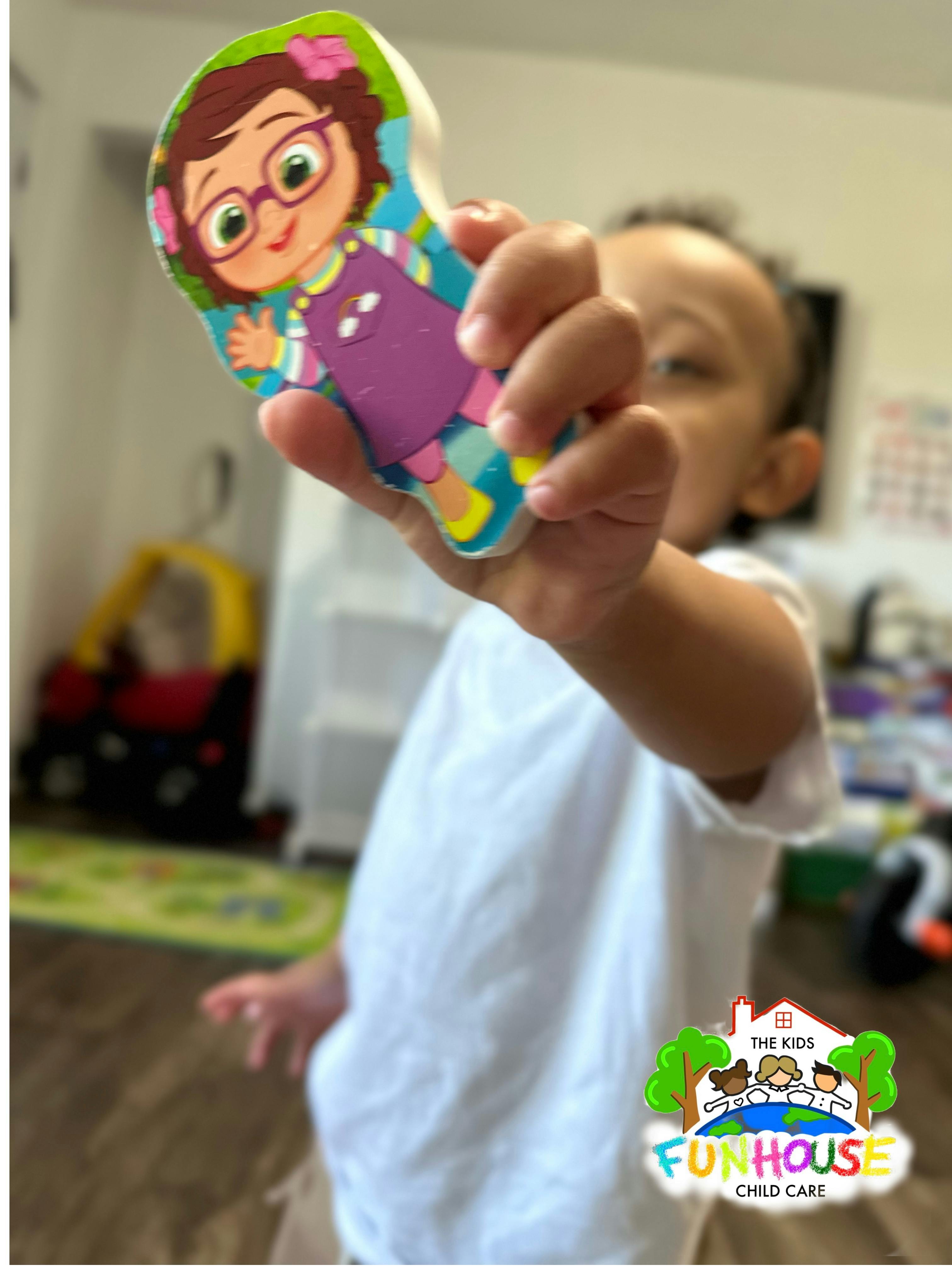Child holding up a colorful cartoon character puzzle piece
