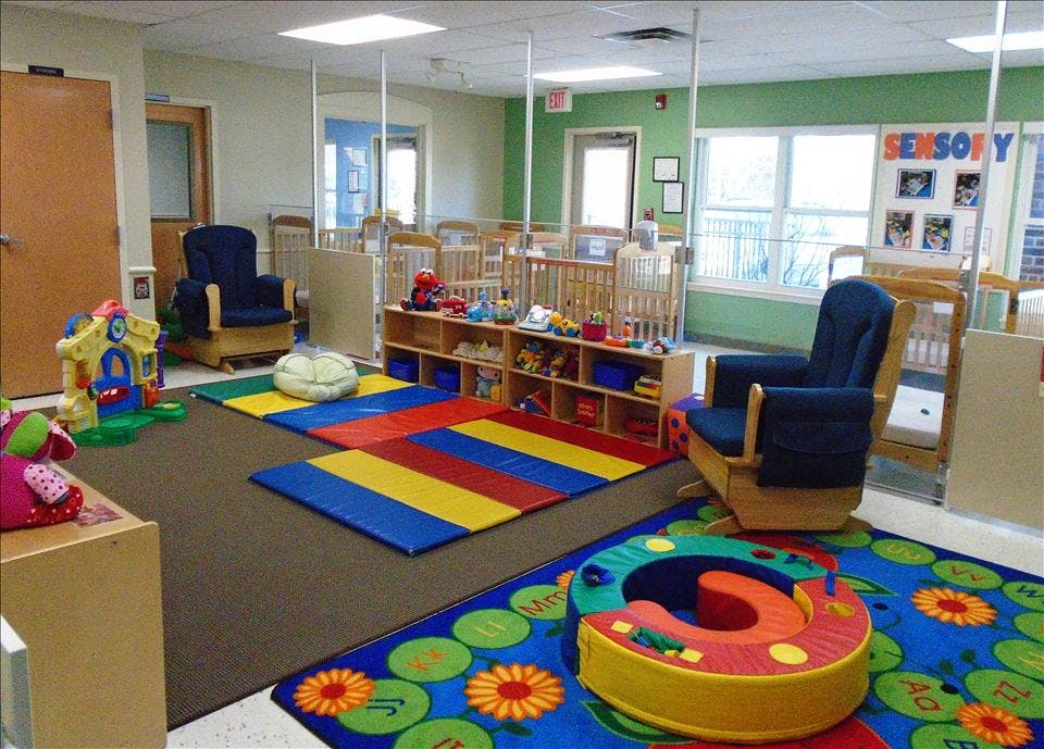 Children's nursery with cots, toys, play mats, and a sign for "SENSORY"