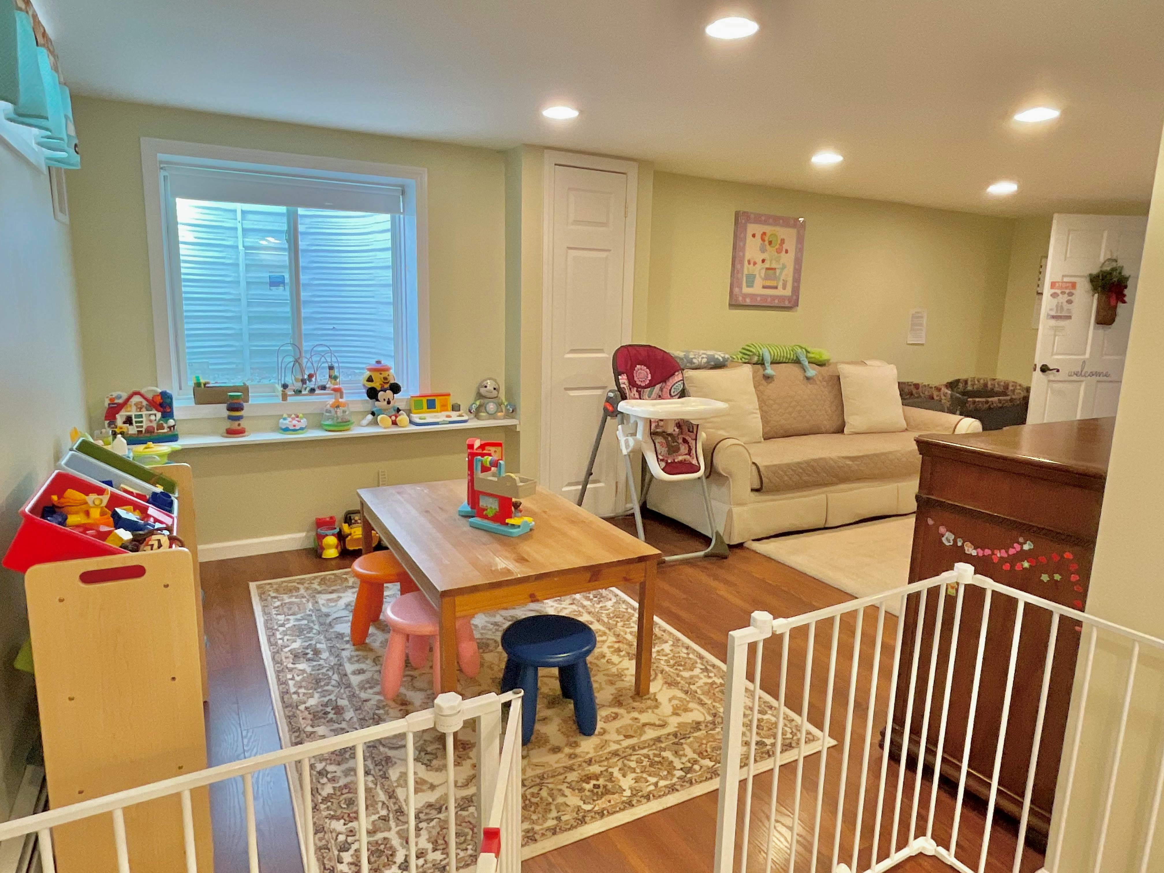 Playroom with a small table and chairs, baby gate, and sofa