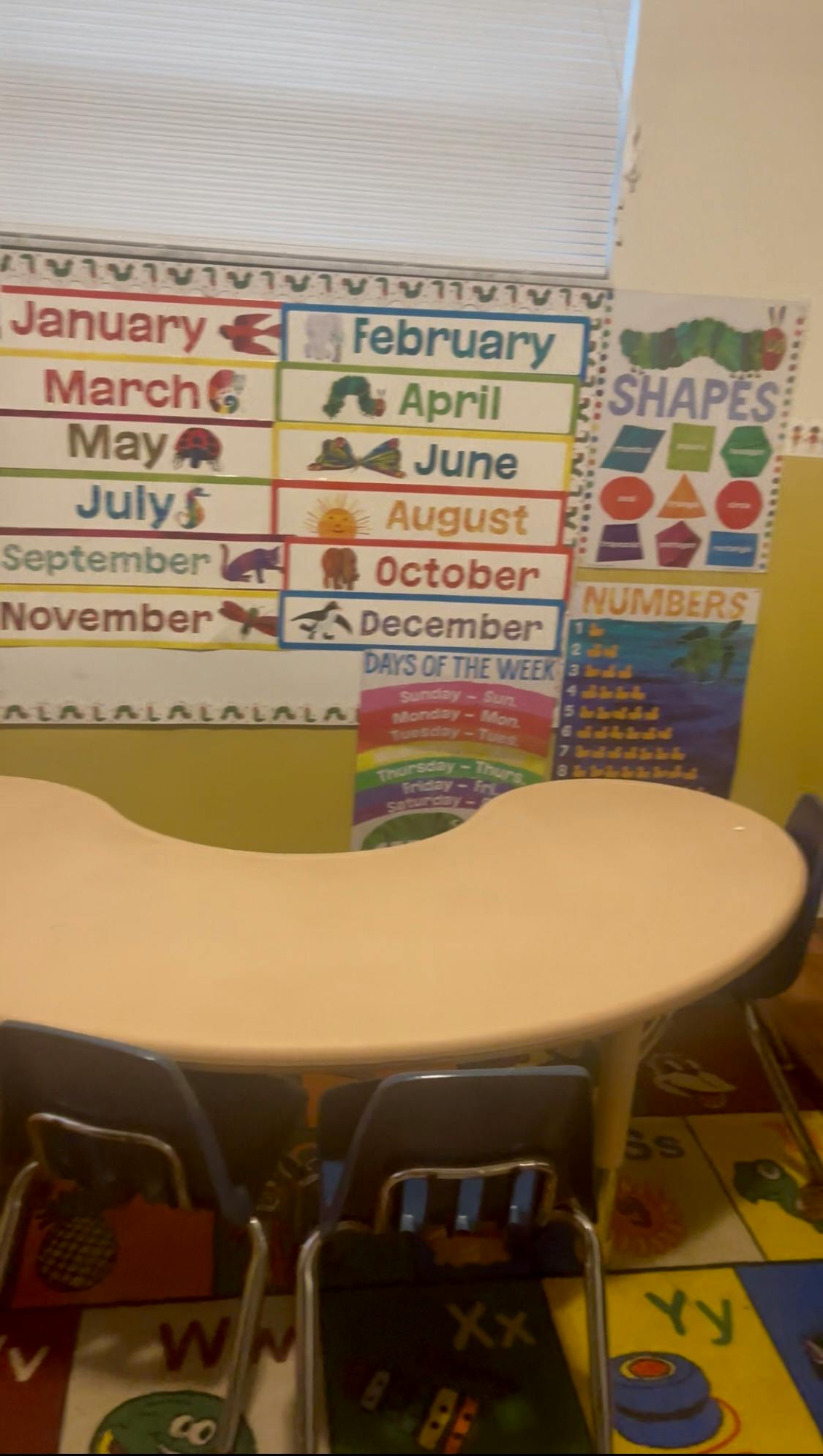 Classroom with a table, chairs, and educational posters on the wall