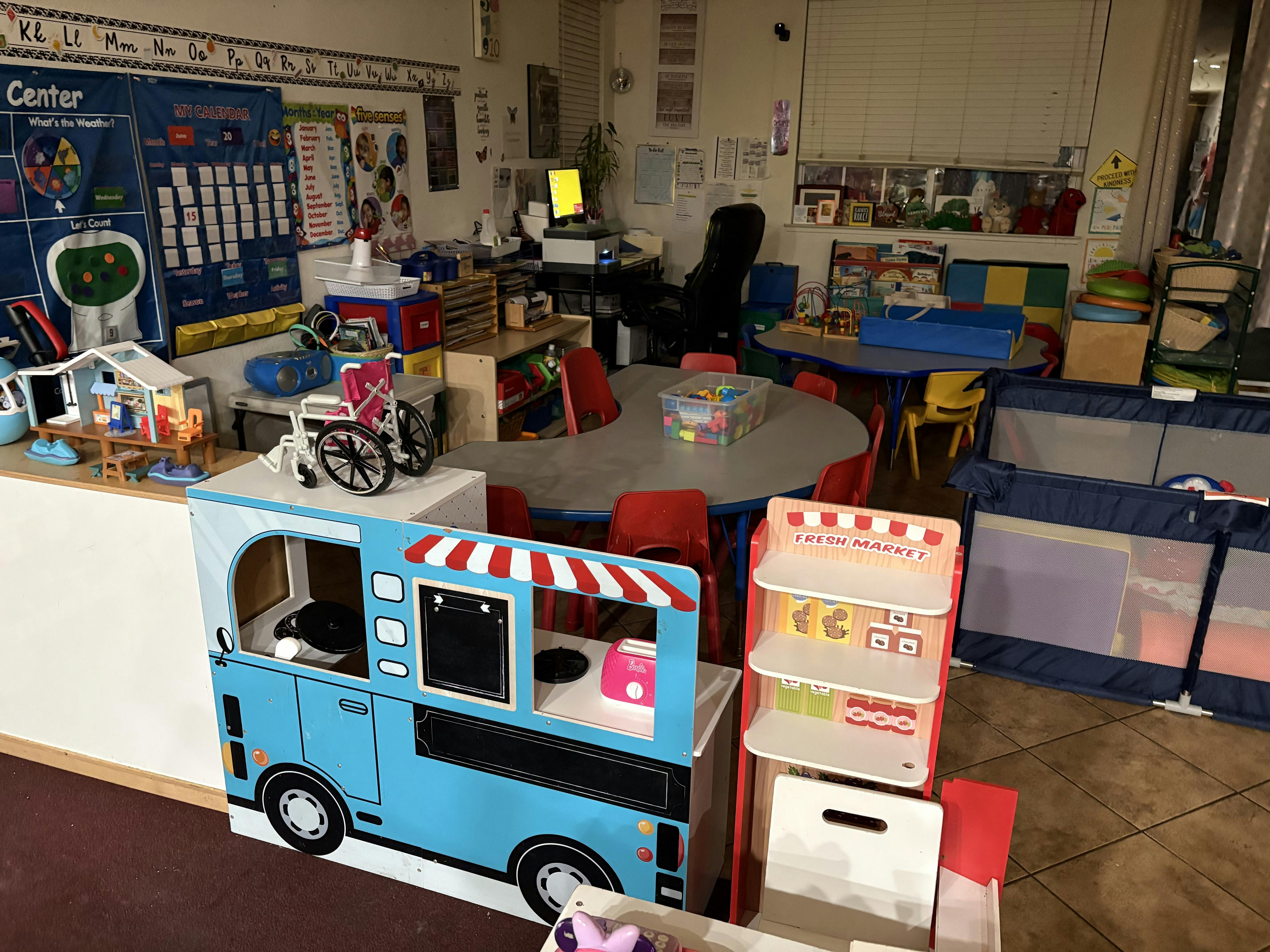 Classroom interior with toy play kitchen and market stands