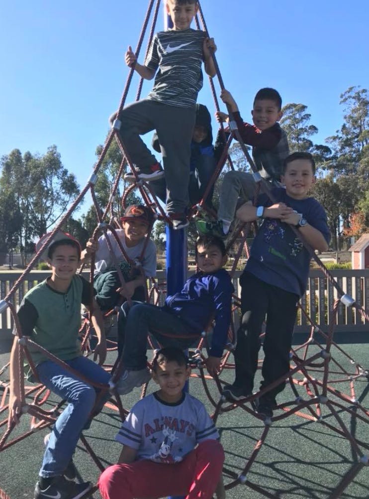 Children climbing on a rope pyramid structure at a playground