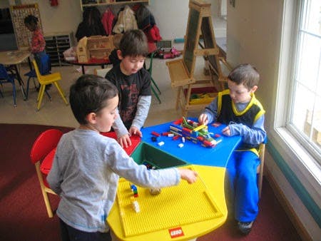 Three children playing with building blocks at a table