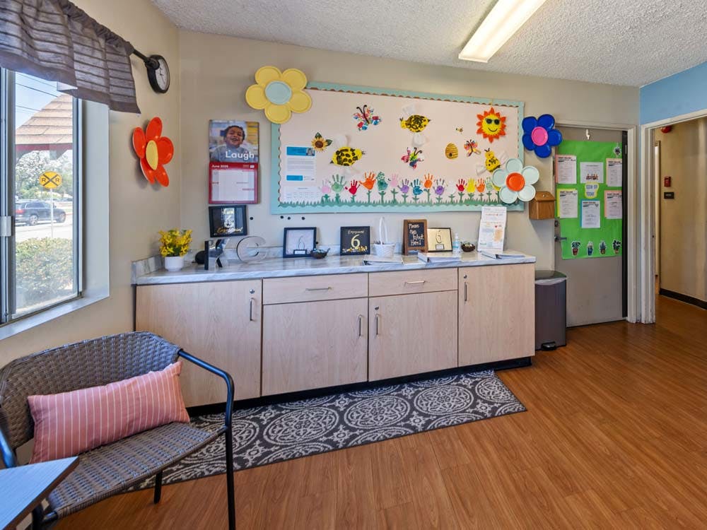 Classroom wall with children's artwork and a bulletin board above cabinets