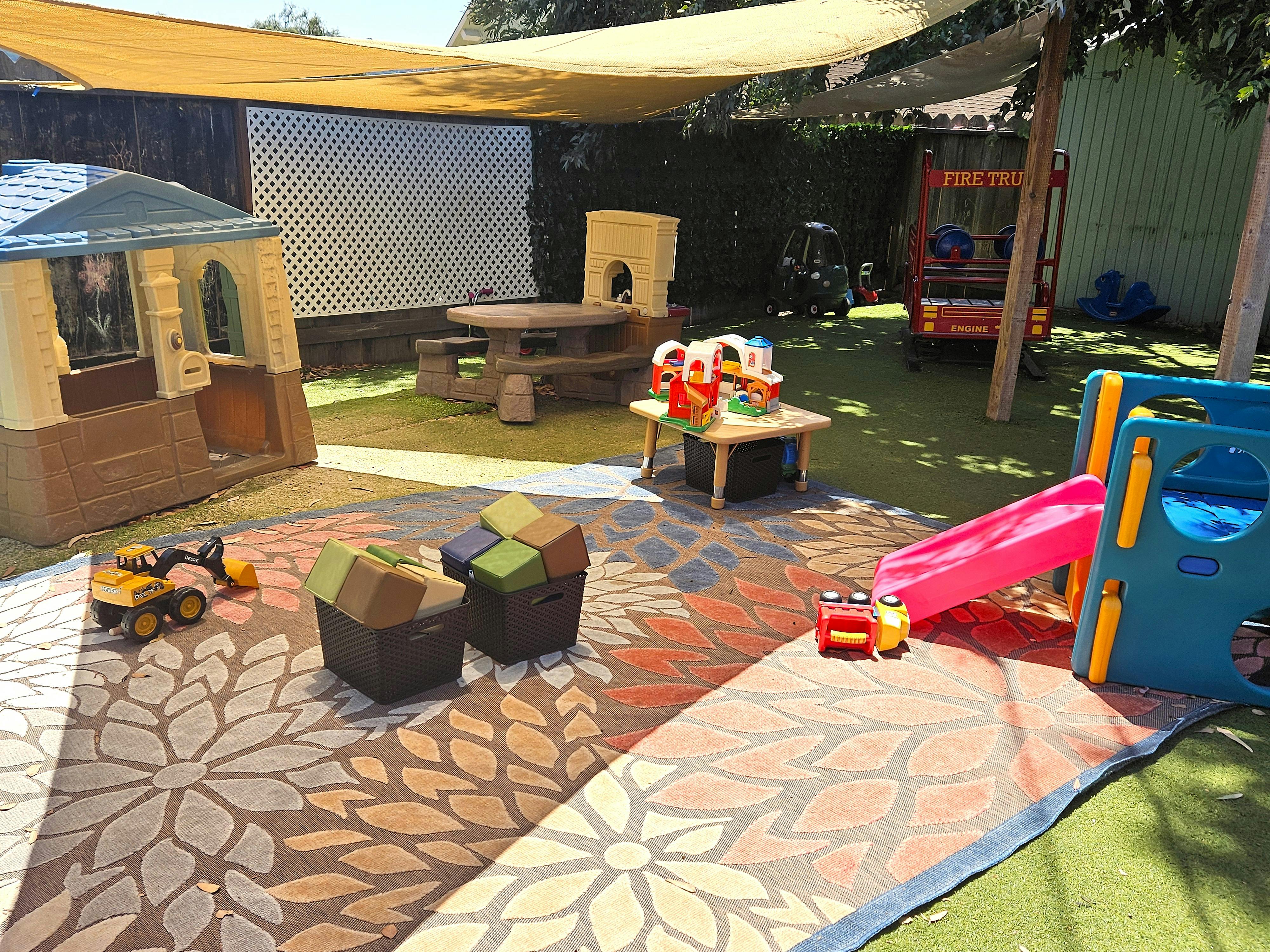Outdoor play area with playhouse, slide, and toys
