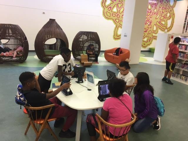 Teens and children using laptops and tablets at a table