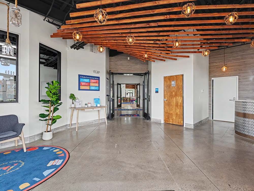 Lobby with concrete floor, wood slat ceiling, and a blue rug with colorful shapes