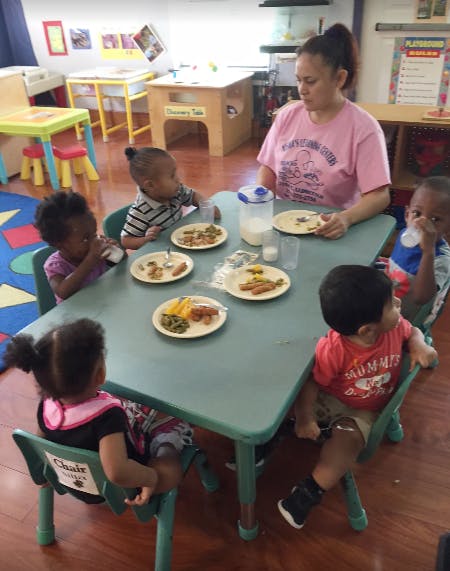 Adult and multiple children sitting at a table with plates of food