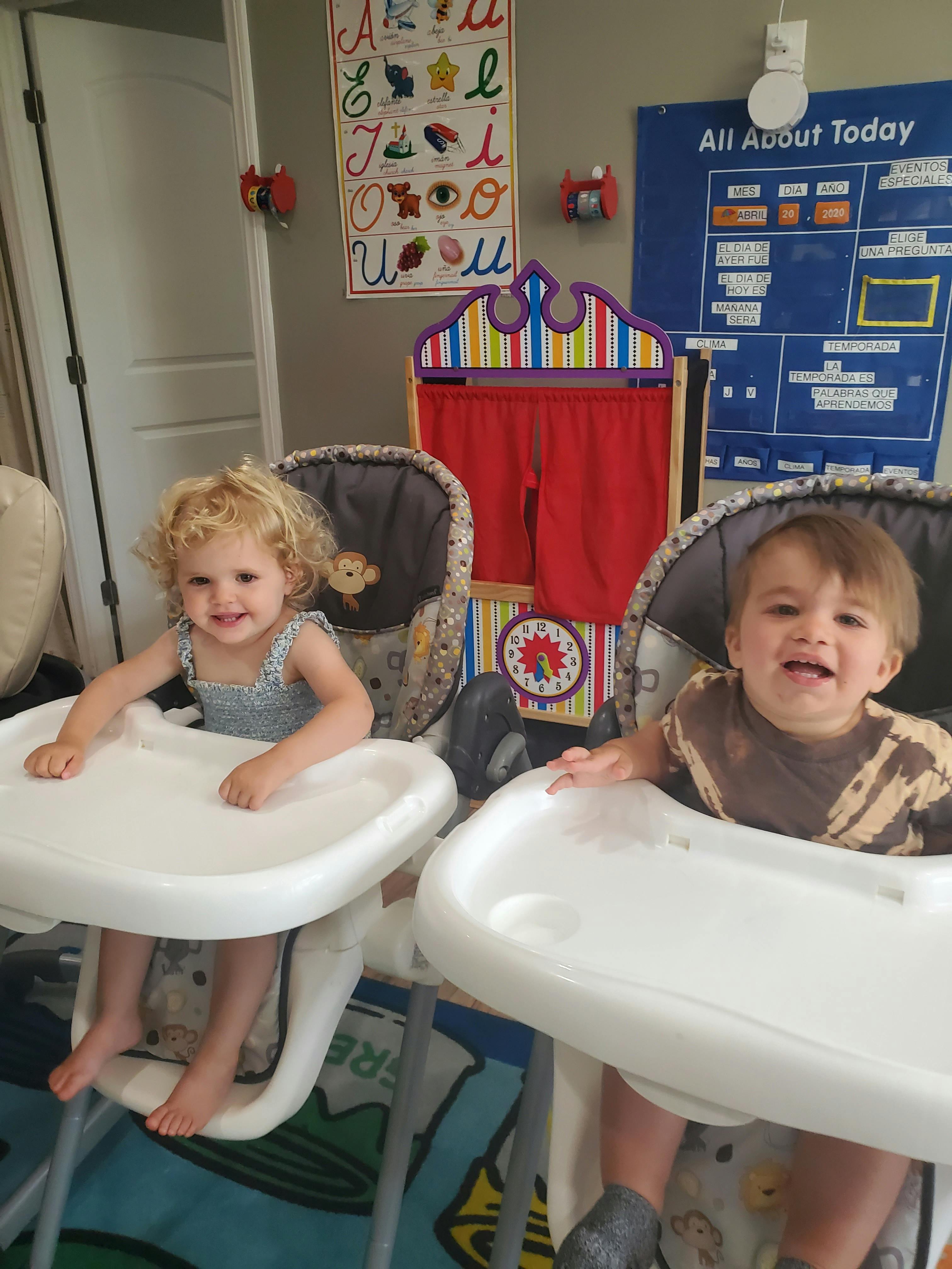 Two children sitting in high chairs