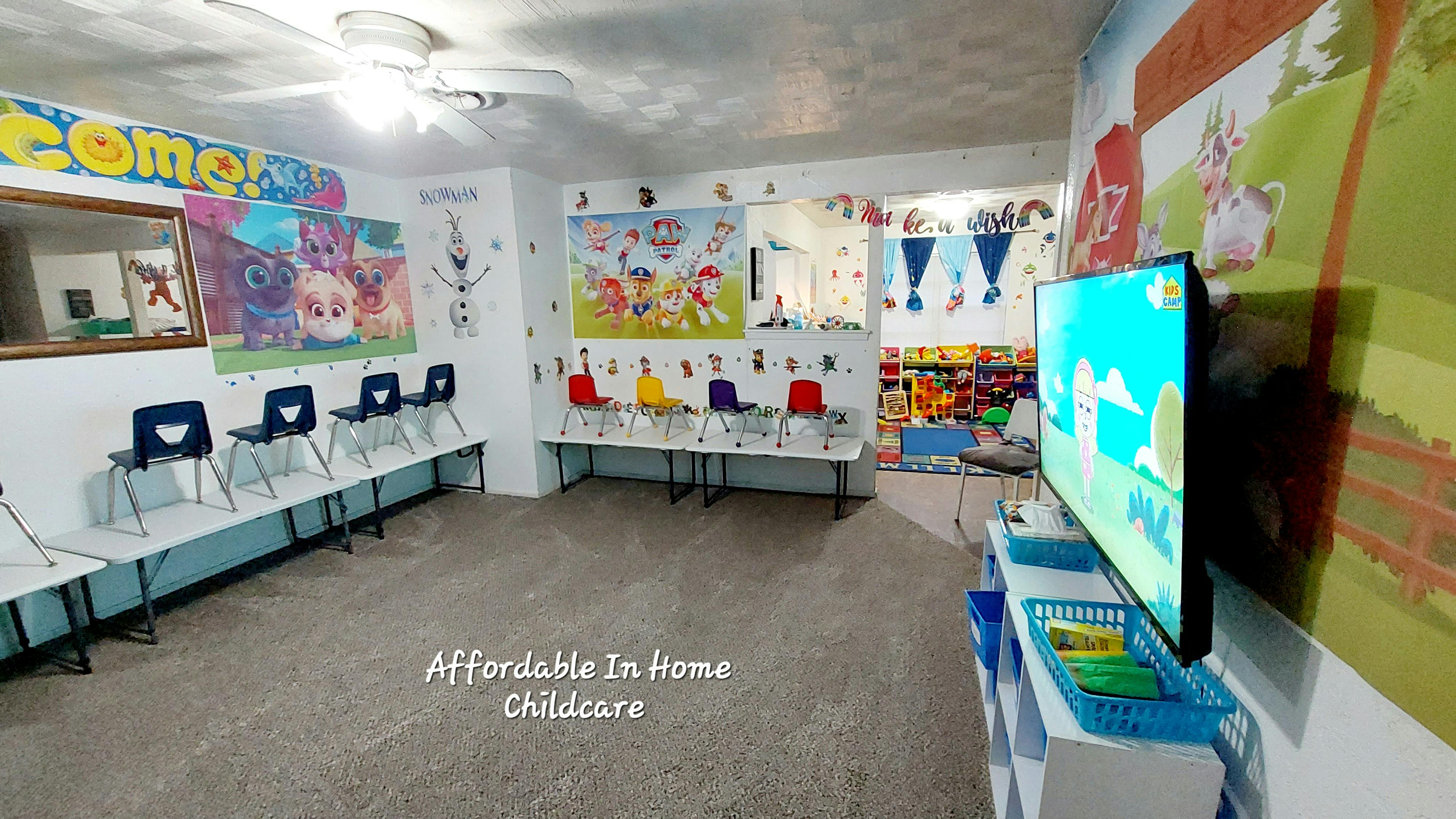 Childcare room with small chairs and tables, decorated walls, and a television