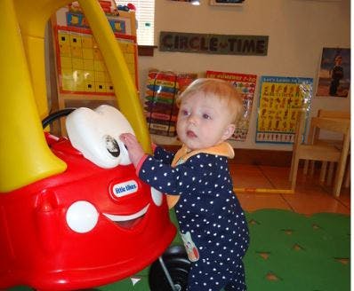Child playing with a red toy car