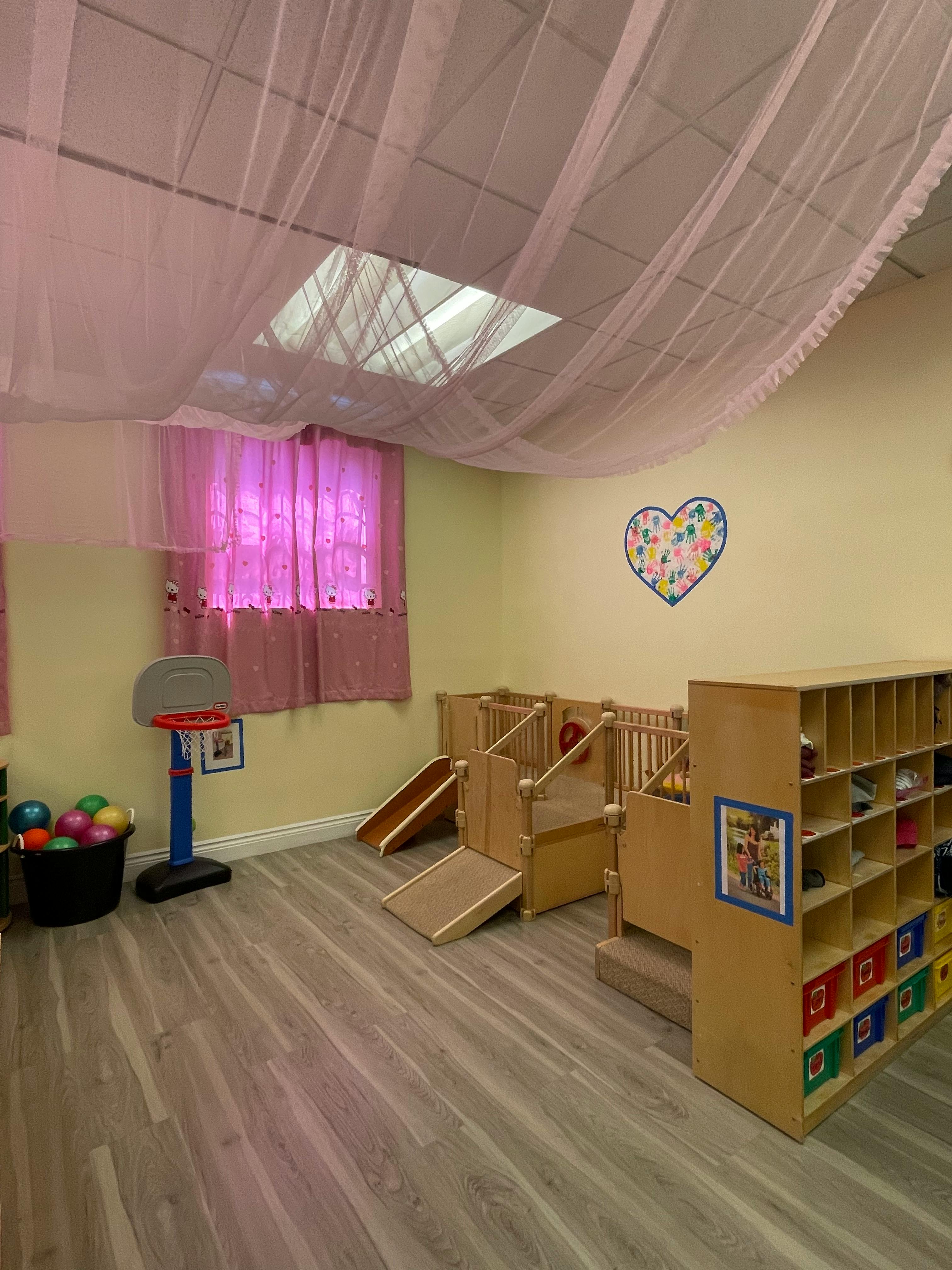 Playroom with small wooden slides, cubbies, and a toy basketball hoop