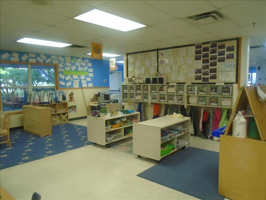 An empty classroom with blue walls, a bulletin board, and small tables