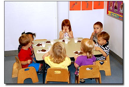 Group of children sitting at a table with food