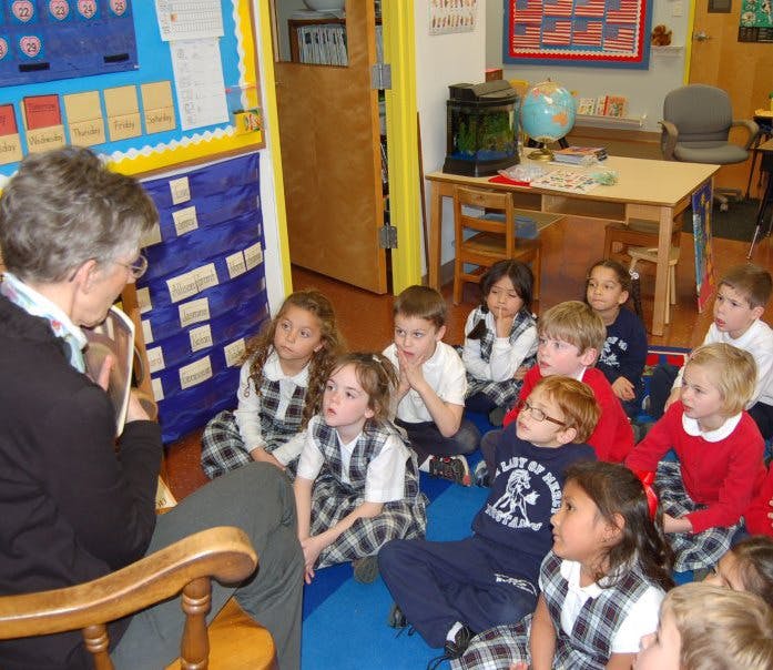 Person reading to a group of children in a classroom