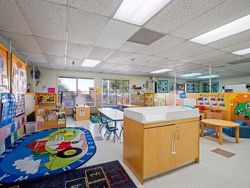 Classroom with tables, a large rug, and a changing station