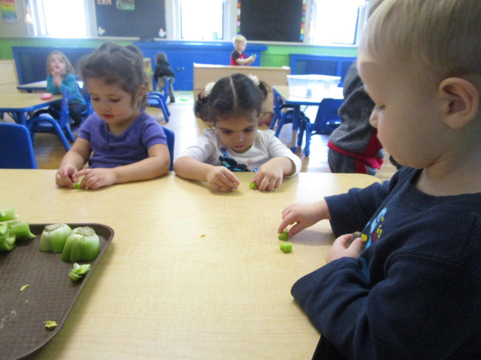 Three children at a table playing with green objects
