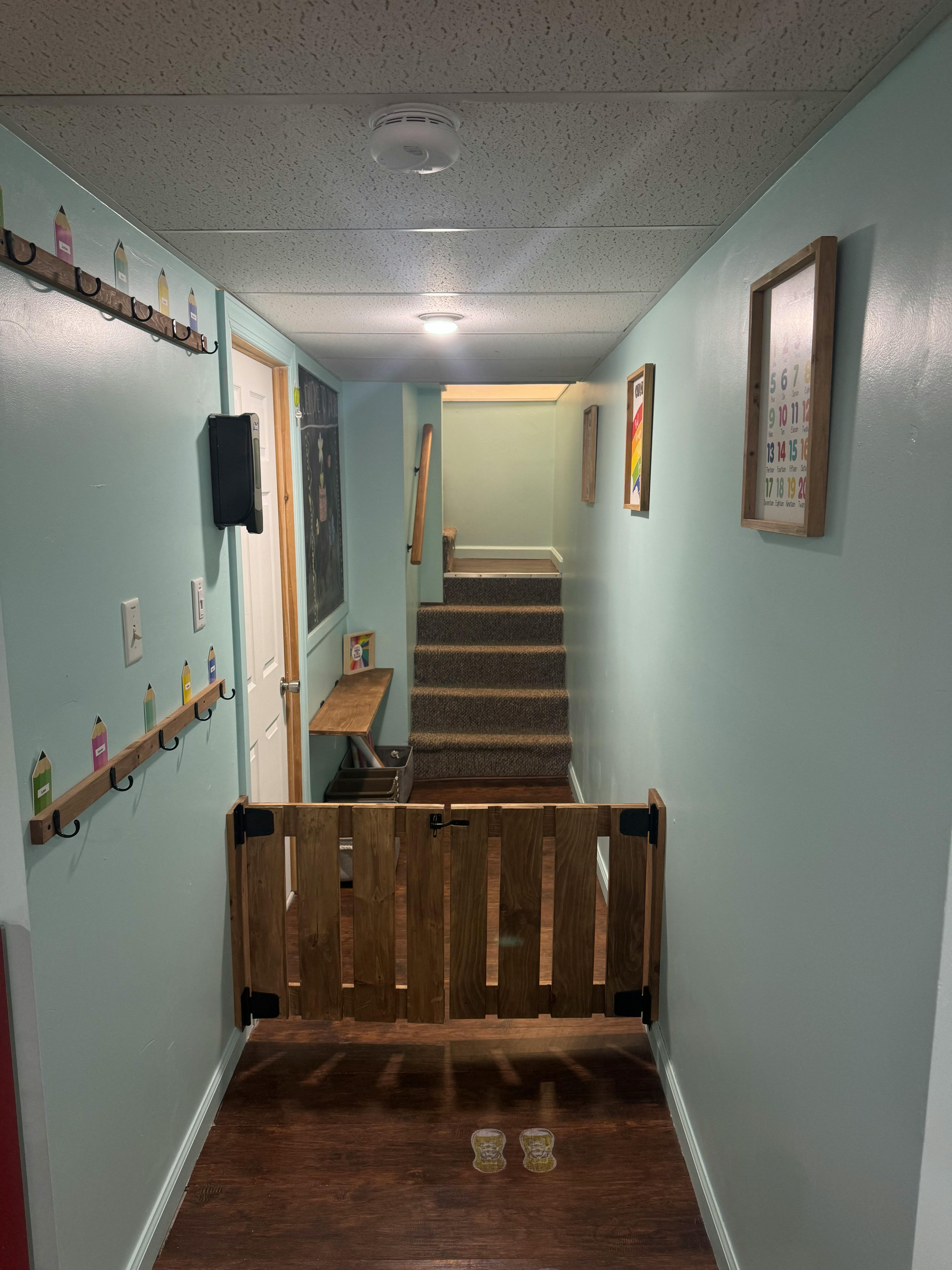Hallway with a wooden baby gate at the bottom of stairs