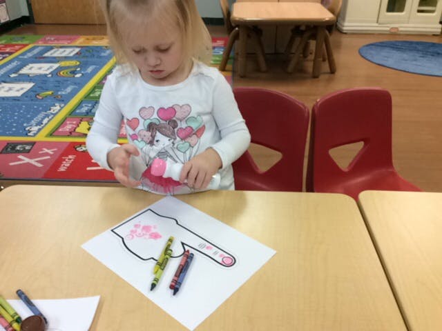 Child painting a paper cutout at a table