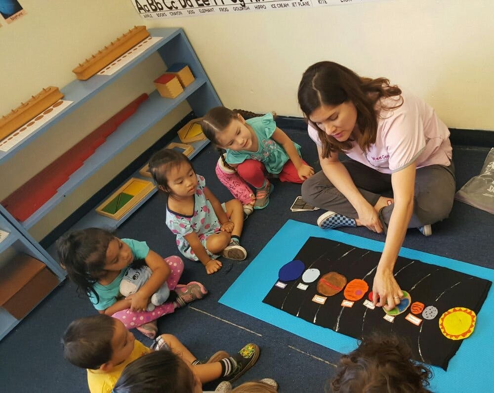 Person teaching children with a solar system model
