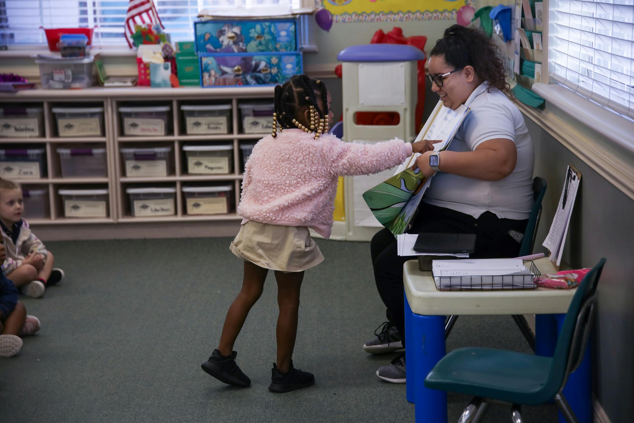 Child handing a paper to an adult in a classroom